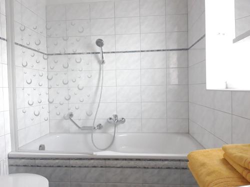 a white bath tub with a shower in a bathroom at Ferienhaus Albrecht in Egg
