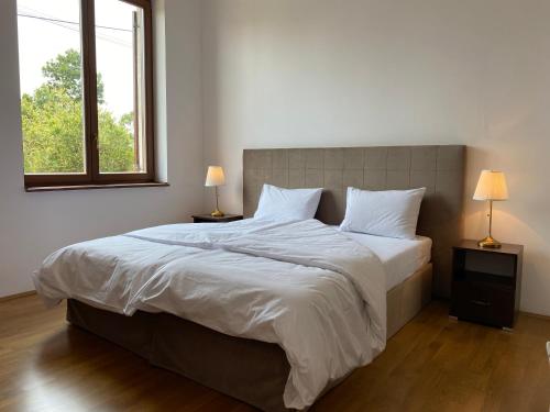 a bedroom with a large white bed with two lamps at Kakasszéki Vendégház in Székkutas