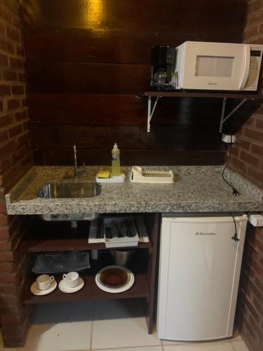 a kitchen counter with a sink and a microwave at Pousada Estação Baleia in Praia do Rosa