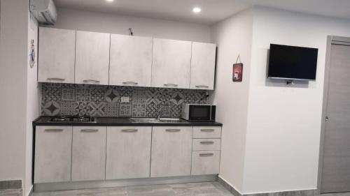 a kitchen with white cabinets and a tv on the wall at Maria e Antonio Blu in Castellammare di Stabia