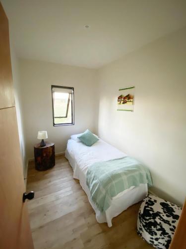 a white bedroom with a bed and a window at Cabañas Vista Volcanes del Sur in Llanquihue