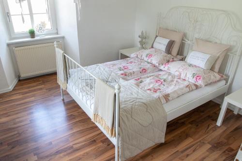 a white bed in a bedroom with a wooden floor at Gutshof Bartl 2 in Klagenfurt