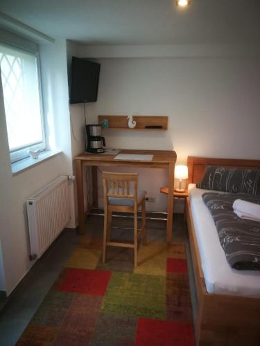 Habitación pequeña con escritorio, cama y silla en Einzelzimmer *Am Bronnwiesle*, en Deggingen