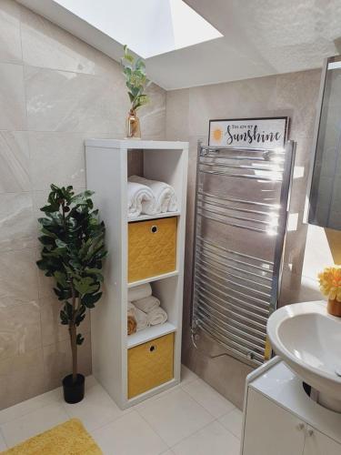 a bathroom with a sink and a shower with towels at Deluxe Spacious Apartment in Chadwell Heath, London in Goodmayes