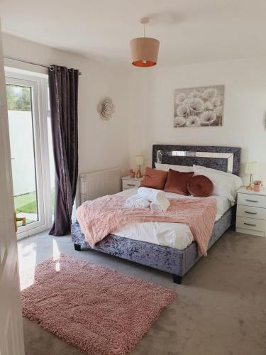 a bedroom with a large bed and a pink rug at Deluxe Spacious Apartment in Chadwell Heath, London in Goodmayes