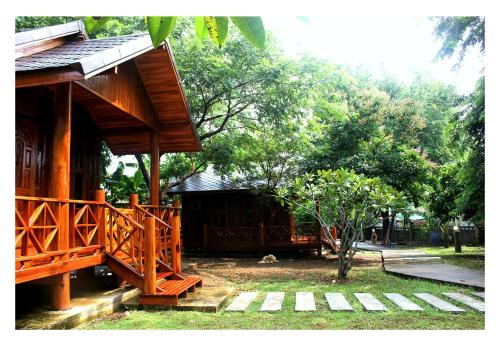 a wooden building with a porch and a tree at Sichang My home in Ko Si Chang