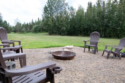 a fire pit with three chairs and a bowl at Alaska Frontier Inn in Delta Junction