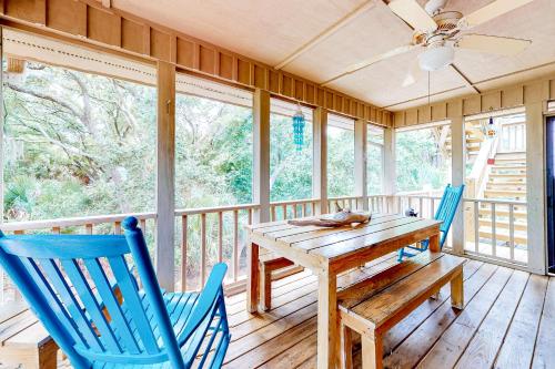 a porch with a wooden table and two blue chairs at Slow Drift in Edisto Beach