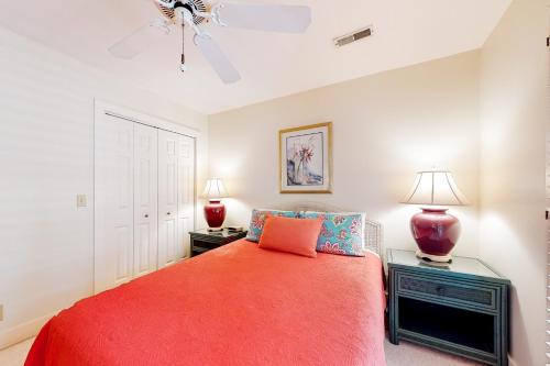 a bedroom with a red bed and two lamps at Slow Drift in Edisto Beach