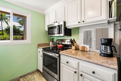 a kitchen with green walls and white cabinets at Keauhou Kona Surf & Racquet Club #58 in Kailua-Kona