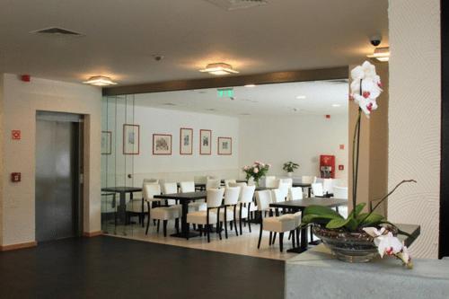 un comedor con mesas y sillas blancas y sin intención de hacerlo en Hotel Arkadia, en Pécs