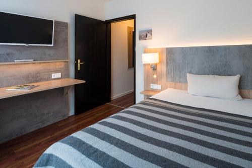 a hotel room with a bed and a flat screen tv at 2Places Side in Lörrach