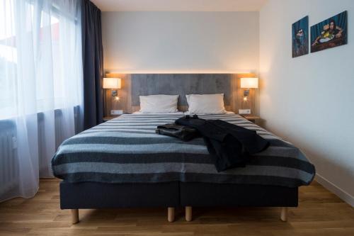 a bedroom with a bed with a blue and white striped blanket at Base I Hotel in Lörrach