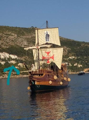 een boot in het water naast een heuvel bij Apartment Perica in Dubrovnik