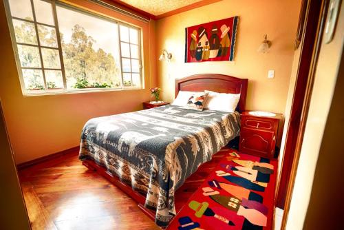 1 dormitorio con cama, ventana y alfombra en Casa de Luis, en Otavalo