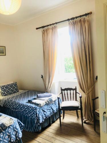 une chambre avec un lit, une chaise et une fenêtre dans l'établissement Le Vieux Manoir, à Carolles