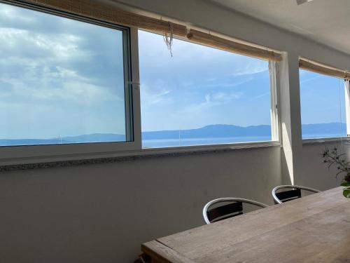 a table and chairs in a room with three windows at Apartments Michael & Petra , Omisalj, Insel Krk, Kroatien in Omišalj