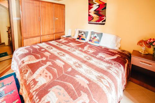 a bedroom with a large bed with a colorful blanket at Casa de Luis in Otavalo