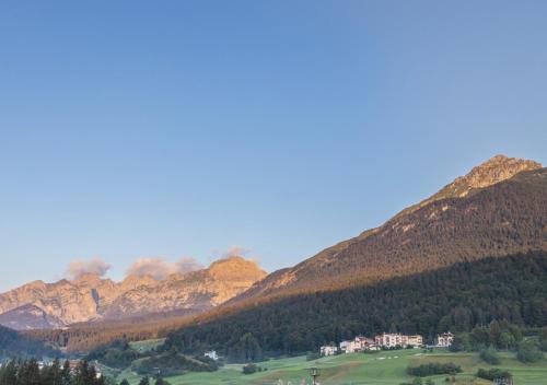 a group of mountains with a house in a field at Garden Wellness Hotel S in Andalo