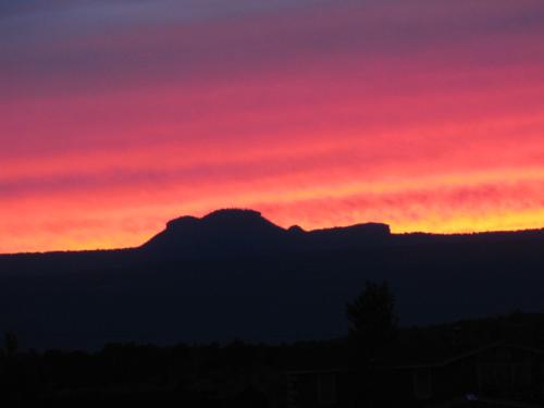 a sunset with a mountain in the background at Cedar Canyon Condos in Blanding