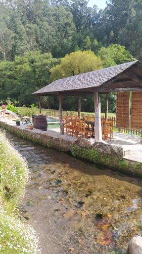 a pavilion with tables and chairs next to a river at A Casa das Augas in Mondoñedo