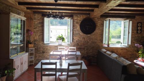 a dining room with a table and chairs and windows at A Casa das Augas in Mondoñedo