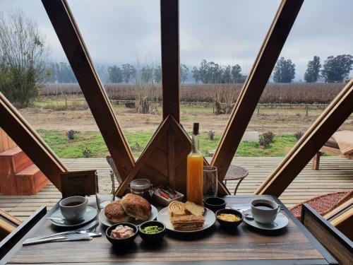 a table with a plate of food on a table with a window at Colchagua Tiny Lodge in Santa Cruz