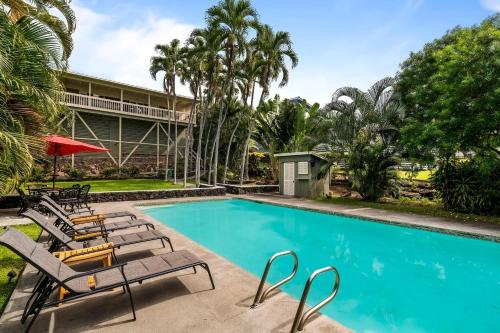 a swimming pool with lounge chairs and a building at Kona Sunset House at Walua in Kailua-Kona