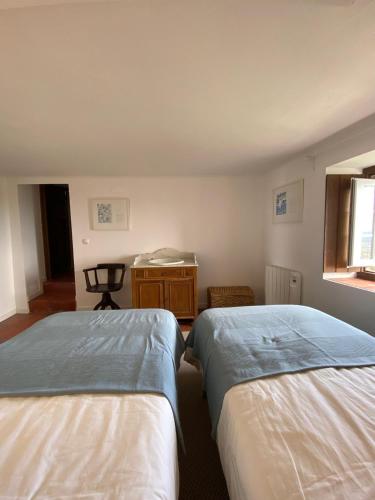 a room with two beds and a desk and a window at Casa do Sétimo Passo in Marvão