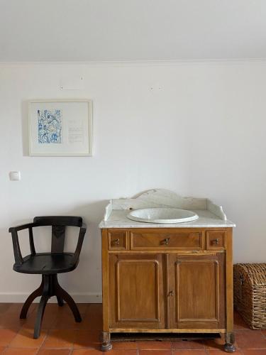 a black chair sitting next to a wooden cabinet with a sink at Casa do Sétimo Passo in Marvão