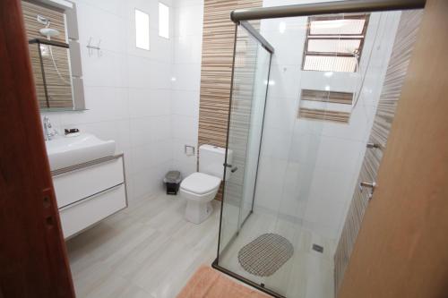 La salle de bains est pourvue de toilettes et d'une douche en verre. dans l'établissement Cantinho da Sônia, à Foz do Iguaçu
