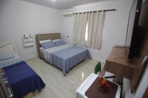 1 dormitorio con 2 camas y TV. en Cantinho da Sônia, en Foz do Iguaçu