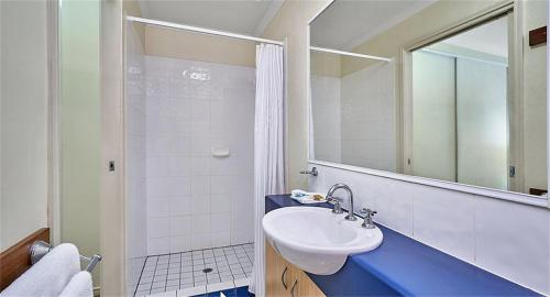 a bathroom with a sink and a shower with a mirror at Trinity Beach Club Holiday Apartments in Trinity Beach