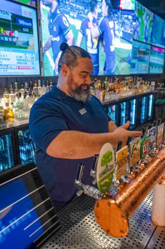 a man standing behind a bar making a drink at Airlie Beach Hotel in Airlie Beach