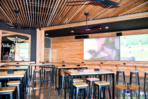 a restaurant with tables and chairs and a large screen at Airlie Beach Hotel in Airlie Beach