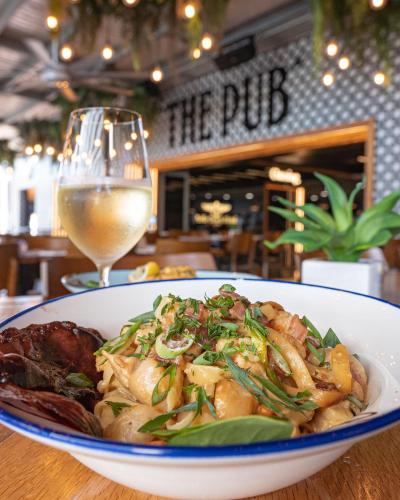 a bowl of food on a table with a glass of wine at Airlie Beach Hotel in Airlie Beach