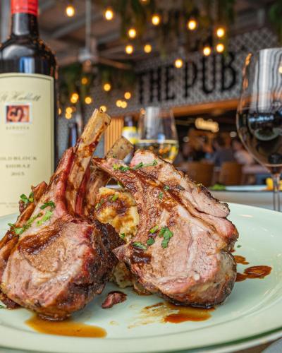 a piece of meat on a plate next to a bottle of wine at Airlie Beach Hotel in Airlie Beach