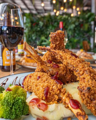 a plate of food with broccoli and a glass of wine at Airlie Beach Hotel in Airlie Beach