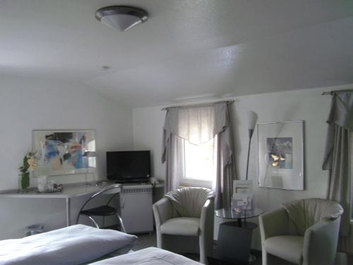 a bedroom with a bed and two chairs and a window at Hotel Ambiente in Hof