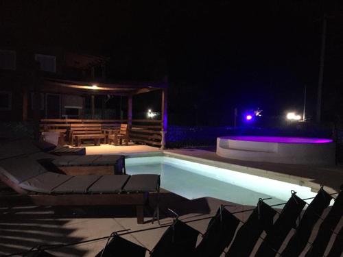 a swimming pool at night with chairs and a table at Posada La Candelaria in Cosquín