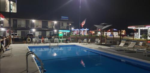 a swimming pool with chairs and a hotel at night at Niagara Falls Courtside Inn in Niagara Falls