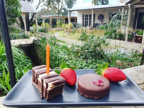 a piece of cake with a candle and strawberries on a plate at Hahndorf House B&B in Hahndorf
