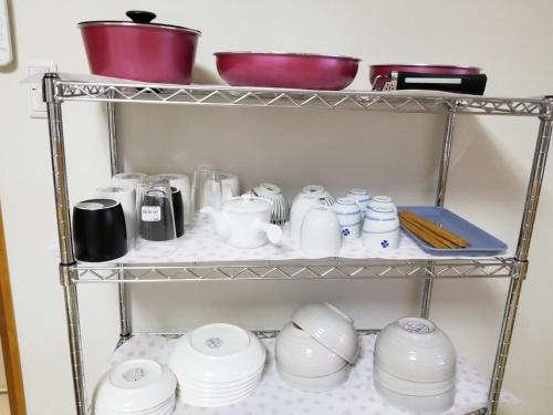 a shelf full of dishes and pots and pans at コンドミニアム海のまんまえ荘 in Ōda
