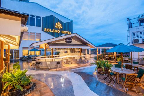 une terrasse avec des tables et des parasols en face d'un hôtel dans l'établissement Solano Hotel, à Lipa