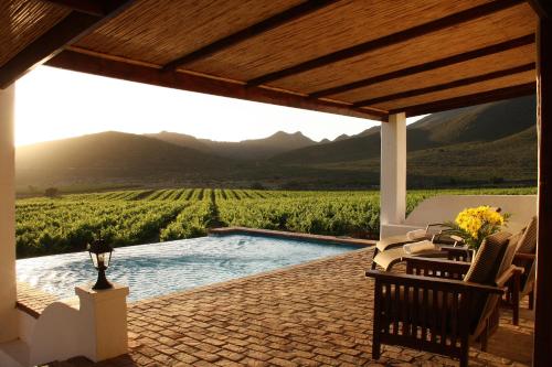 a patio with a pool and a view of a vineyard at Orange Grove in Robertson