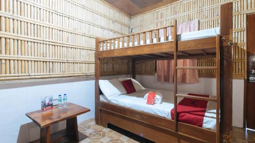 RedDoorz Hostel @Megans Paradisio Beach Resort في Zambales: غرفة نوم بسريرين بطابقين وطاولة