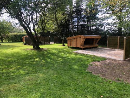 un parc avec un banc et un arbre dans l'herbe dans l'établissement Familiehuis Boysen Shelters, à Ribe