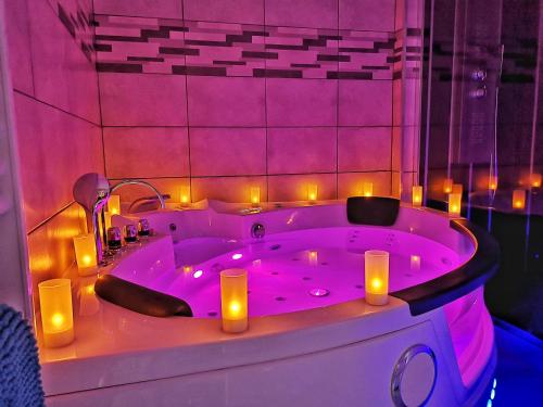 een paarse badkamer met een bad met kaarsen erin bij ☆ OURS & SPA ☆ COSY ☆ MAGIC ☆ LOCBNB ☆ in Barr