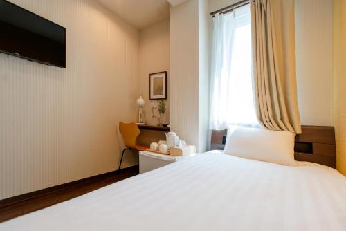 a bedroom with a large white bed and a window at ELE Hotel 東上野 in Tokyo