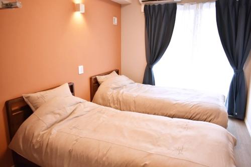 two beds in a room with a window at GEORGE HOUSE in Tsuji in Naha